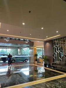 a man standing in a lobby with a car parked in a garage at The Avenue Parkland Serpong by Ngeroomin in Babakan
