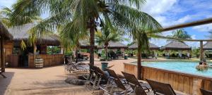 a resort pool with chairs and a palm tree at Eco Park Campo Grande Hotel in Campo Grande