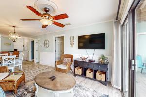 a living room with a ceiling fan and a table at Romar Beach 205 in Gulf Shores
