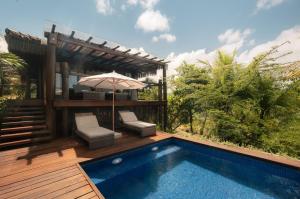 un patio con sombrilla y piscina en Txai Resort, en Itacaré