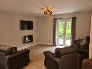 een woonkamer met een bank en stoelen en een raam bij Modern 2 bedroom Apartment with River views in Behy Bridge