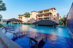 a large swimming pool with chairs in front of a building at Apartamento Beverly Hills - Porto das Dunas in Mangabeira