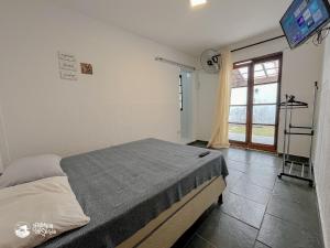 a bedroom with a bed and a tv on the wall at Linda suíte à 300m da Praia do Pequeá no Saco da Capela in Ilhabela +13 photos