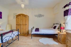 een slaapkamer met 2 bedden en een houten kast bij Farriers Cottage in Blofield