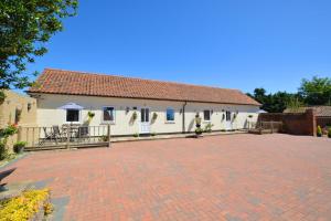 een wit gebouw met een rood dak en een stenen oprit bij Farriers Cottage in Blofield