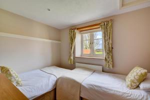 two beds in a small room with a window at Folly Cottage in Bodham