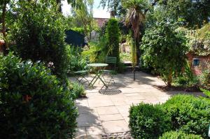 a patio with a table and chairs in a garden at Folly Cottage in Bodham