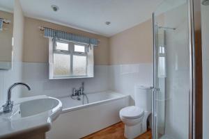a bathroom with a tub and a toilet and a sink at Folly Cottage in Bodham +10 photos
