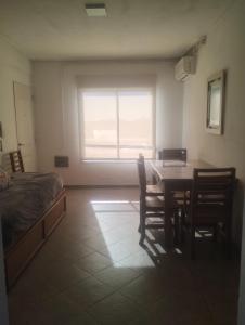 a bedroom with a table and chairs and a window at Dpto Zapiola - 2 Ambientes 3er piso por escalera in Bahía Blanca