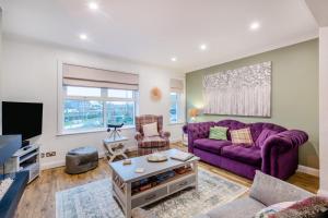ein Wohnzimmer mit einem lila Sofa und einem TV in der Unterkunft Quayside Cottage in Rye