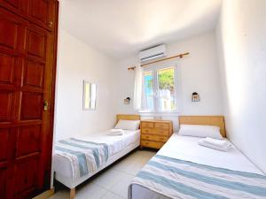 two beds in a room with a window at Ca L'Anxoveta - casa amb piscina a prop de la platja a l'escala in L'Escala +6 photos