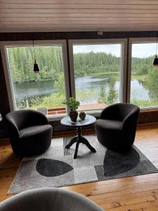 a living room with two chairs and a table and two windows at Cozy lakeside cabin in Trøndelag  +10 photos