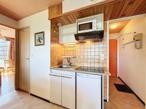 Una pequeña cocina con fregadero y microondas. en Résidence Pegase - APPARTEMENT 2 PIECES 5 PERSONNES MAE-9724, en Le Corbier