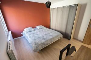 BreslesにあるAppartement de charme avec extérieurの赤い壁の小さなベッドルーム(ベッド1台付)