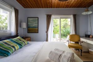 a bedroom with a bed and a desk and windows at 4 Bedroom Stoney Creek Nature Oasis Sauna, Games & Luxury Comfort in Hamilton