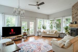 a living room with white furniture and a tv at 4 Bedroom Stoney Creek Nature Oasis Sauna, Games & Luxury Comfort in Hamilton