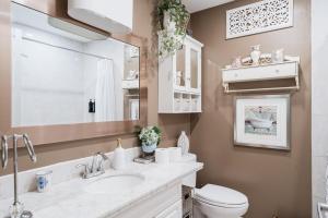a bathroom with a sink and a toilet and a mirror at 4 Bedroom Stoney Creek Nature Oasis Sauna, Games & Luxury Comfort in Hamilton +56 photos