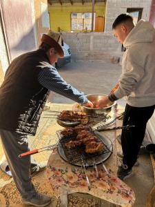 a man and a woman cooking food on a grill at Salmanya in Bokonbayevo