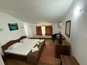 a bedroom with a bed and a desk and a television at Pensiunea Restaurant Casa Lacului in Malaia
