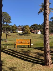 a bench in a park next to a tree at Pequena Suíça Hotel Boutique in Chácara