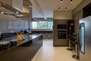 a large kitchen with black counters and a brick wall at Studio Luggo Pampulha in Belo Horizonte