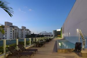 a balcony with chairs and a swimming pool on a building at Studio Luggo Pampulha in Belo Horizonte