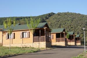 a row of wooden cottages with a mountain in the background at Lincetur Cabañeros - Centro de Turismo Rural in Navas de Estena