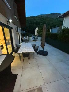 Un patio con una mesa y sillas y una sombrilla. en Aux pieds des montagnes, en Saint-Michel-de-Maurienne