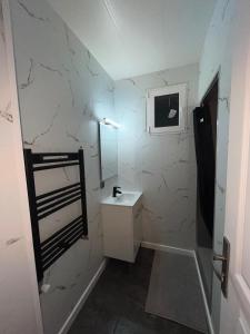 Un baño blanco con lavabo y espejo. en Aux pieds des montagnes, en Saint-Michel-de-Maurienne