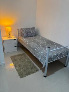 un petit lit dans une chambre avec une lampe et une table dans l'établissement Prático e Aconchegante, à Porto Alegre 8 autres photos