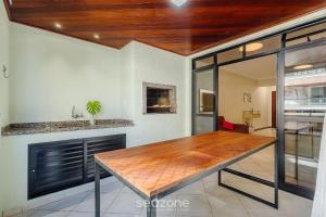 a dining room with a wooden table in a room at Apto c varanda e churrasq em cond beira mar UAR301 in Itapema