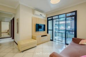 a living room with a tv and a couch at Apto c varanda e churrasq em cond beira mar UAR301 in Itapema