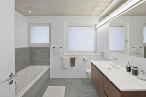 a white bathroom with a tub and a sink at Sera Lodge in Grächen
