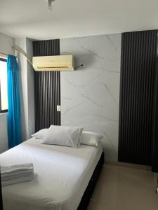 a bedroom with a white bed with a marble wall at APARTAMENTO CÉNTRICO con PISCINA a UNA CUADRA in Santa Fe de Antioquia