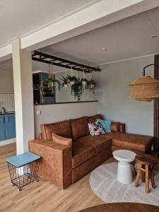 ein Wohnzimmer mit einem braunen Sofa und einem Tisch in der Unterkunft Hofstay Twente in Goor