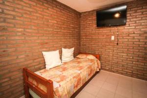 a bedroom with a bed and a brick wall at Nélida Dpto 1 in Villa Carlos Paz