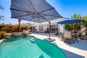 a swimming pool with an umbrella and a table and chairs at La Quinta Fairways in La Quinta