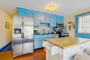 eine Küche mit blauen Schränken und einem Kühlschrank aus Edelstahl in der Unterkunft The Blue Cottage in Provincetown