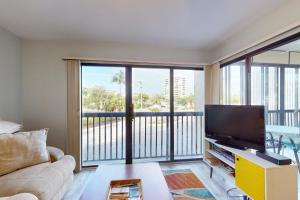 a living room with a couch and a flat screen tv at Santa Maria Condo 102 in Fort Myers Beach