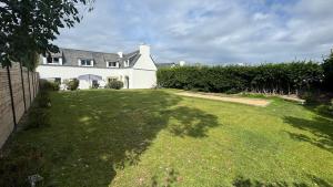 a large yard with a white house with a grass yard at Ty Glaz - Maison Bord de mer avec jardin, proche plage in Roscoff