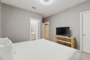 een slaapkamer met een wit bed en een flatscreen-tv bij Barateria 301 in Destin