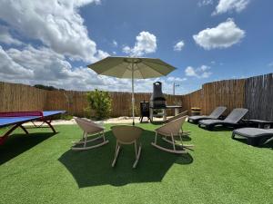 a patio with chairs and a table and an umbrella at אלמה בוטיק - וילה מהממת עם בריכה פרטית מחוממת ומקורה in Shelomi
