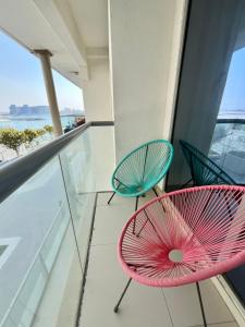 Dos sillas en un balcón con vista al mar. en Elegant 2 Bedroom Duplex Apartment Pacific Al Marjan Island, en Ras al Khaimah
