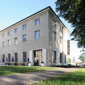 un grande edificio bianco con un albero di fronte di Hotel The Lodge Vilvoorde a Vilvoorde