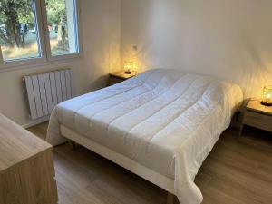 滨海苏拉克Résidence La Grande Combe - 149 - Élégante maison rénovée avec goût et son parc verdoyant MAE-0101的卧室配有白色的床和2张桌子