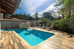 a swimming pool with chairs next to a house at Casa com Piscina climatizada , Jacuzzi 4 Quartos. in Bertioga