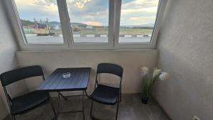 a table and chairs in a room with two windows at Apartament Alb&Negru in Sebeş +4 photos