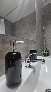 a soap dispenser sitting on a bathroom sink at Apartament Alb&Negru in Sebeş