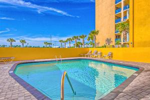 a swimming pool with chairs and a building at Emerald Skye 42 in Orange Beach