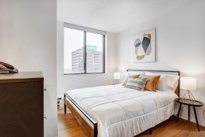 a white bedroom with a large bed and a window at LaCité Cozy Apartment Close to Central Montreal in Montréal +83 photos